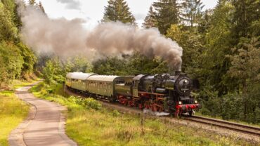 Das Bild zeigt den Museumszug mit Dampflok 52 8154 bespannt in einer Steigung im Wald nach Oberhof.